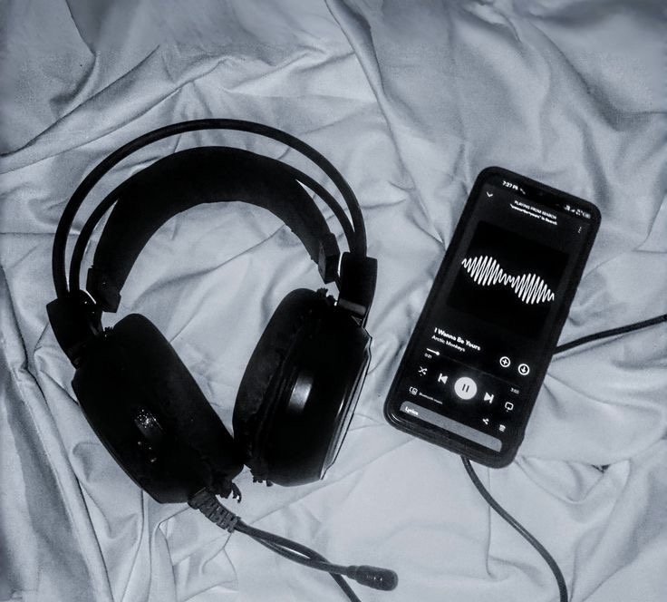 Cuffie e telefono sul letto che riproducono musica, ispirazione da una frase di una canzone sulla crescita personale